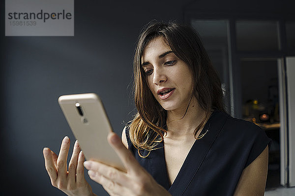 Porträt einer jungen Frau  die auf ein Mobiltelefon schaut