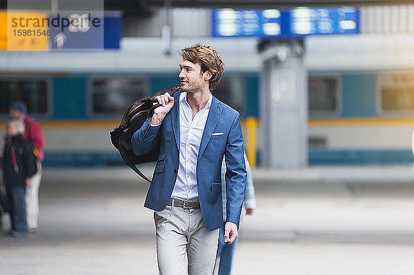 Porträt eines jungen Geschäftsmannes mit Tasche am Bahnhof