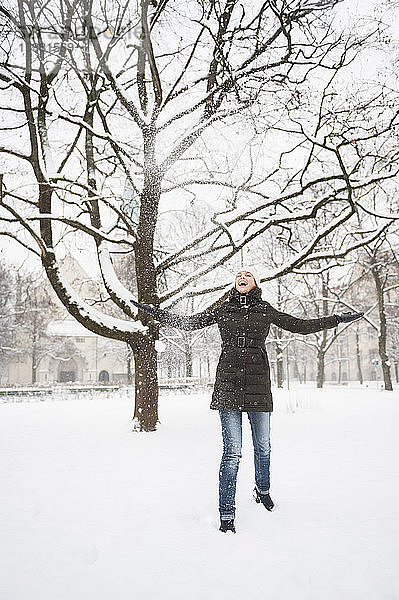 Lachende Frau  die Schnee in die Luft wirft