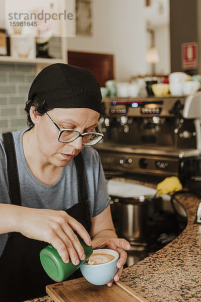Porträt einer Kellnerin bei der Zubereitung von Cappuccino in einem Café