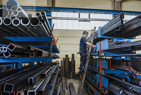 Mann arbeitet mit Metallstangen auf einem Regal in einer Fabrik