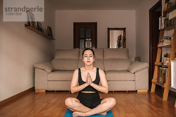 Selbstbewusste Frau meditiert in Gebetshaltung zu Hause