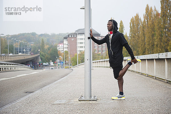 Junger Jogger streckt sein Bein in der Stadt