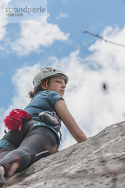 Junge Frau klettert auf Felsen gegen den Himmel