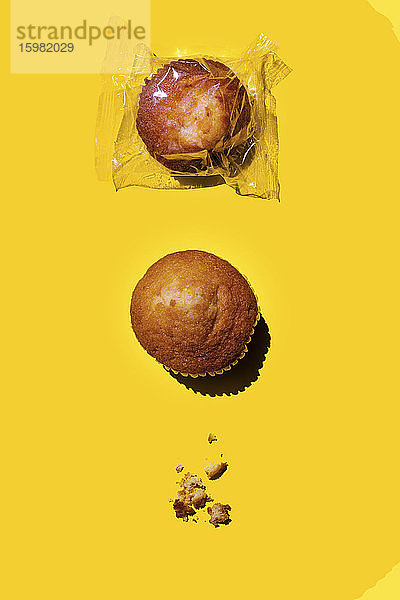 Studioaufnahme von zwei Muffins und Krümeln anstelle des dritten Muffins