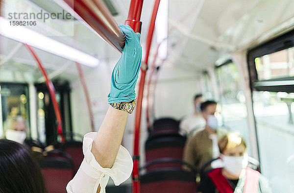 Junge Frau trägt Schutzhandschuhe in einem öffentlichen Bus  Spanien