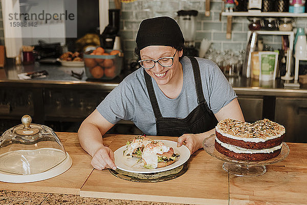 Porträt einer lächelnden Kellnerin  die in einem Café Essen serviert