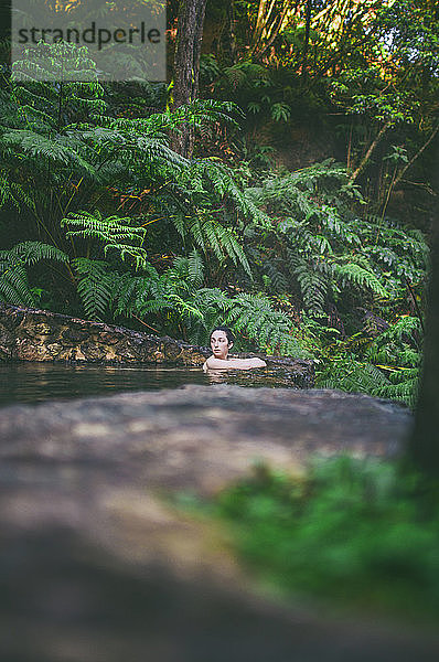 Junge Frau beim Baden in einer heißen Quelle  Caldeira Velha  Insel Sao Miguel  Azoren  Portugal