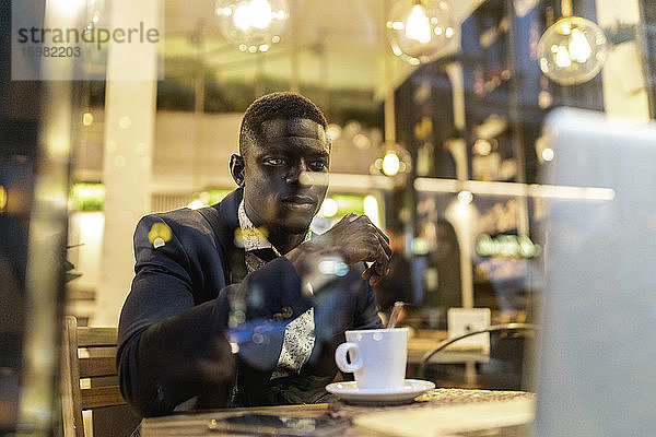 Porträt eines jungen Geschäftsmannes  der in einem Café an einem Laptop arbeitet