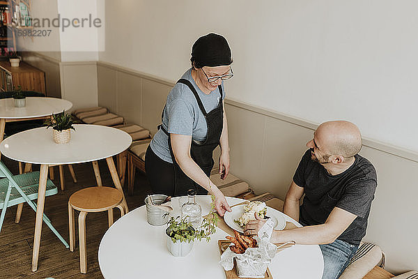 Lachende Kellnerin beim Servieren von Essen in einem Café
