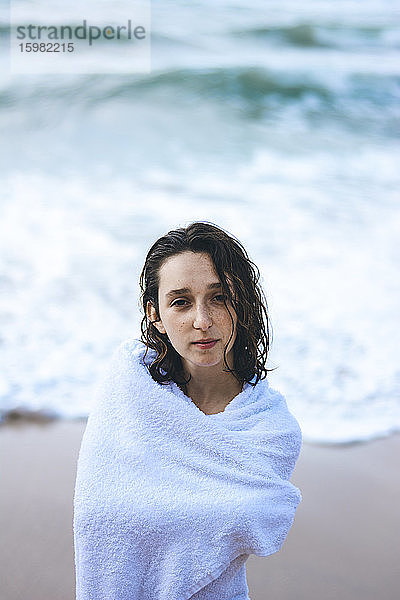 Junge Frau  eingewickelt in ein weißes Handtuch  am Praia da Ursa  Lisboa  Portugal