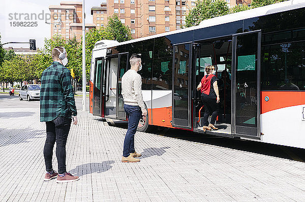 Fahrgäste mit Schutzmasken beim Einsteigen in einen Linienbus  Spanien