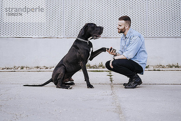 Junger Mann unterrichtet seinen Hund im Freien
