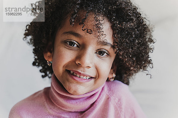 Porträt eines lächelnden kleinen Mädchens mit rosa Rollkragenpullover
