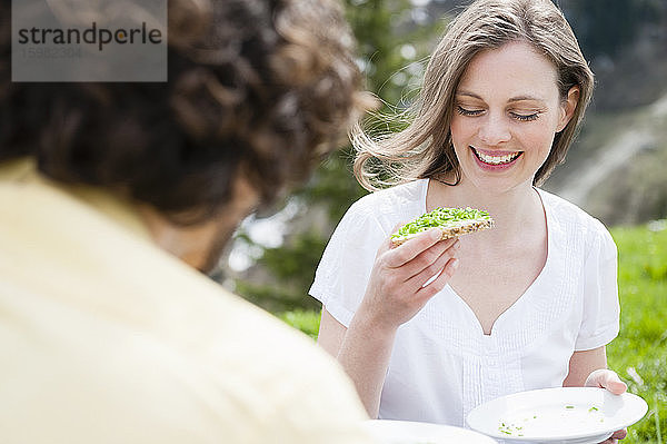 Lächelnde schöne Frau  die einen Snack isst  während sie ein Picknick mit einem Mann genießt