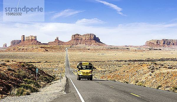 Schulbus auf Wüstenstraße im Monument Valley Tribal Park gegen den Himmel  Utah  USA