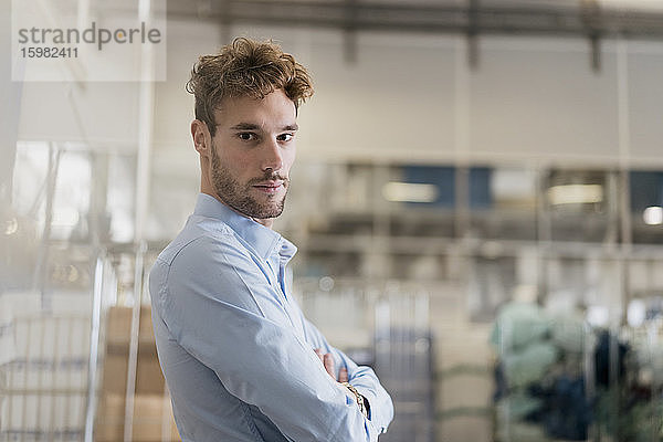 Porträt eines selbstbewussten jungen Geschäftsmannes in einer Fabrik