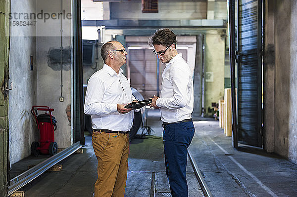 Zwei Geschäftsleute bei einem Treffen in einer Fabrikhalle