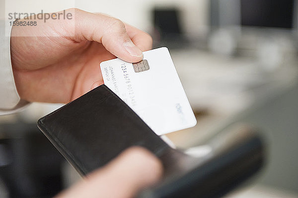 Ein Mann hält eine Brieftasche und eine leere weiße Kreditkarte in den Händen.