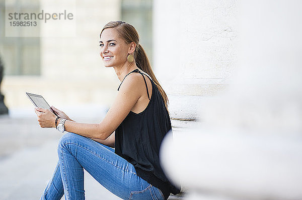 Porträt einer lächelnden Frau mit digitalem Tablet in der Stadt