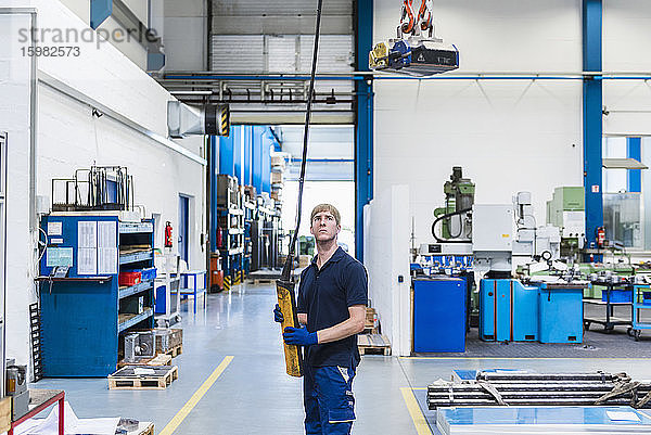 Mann arbeitet mit Hallenkran in einer Fabrik