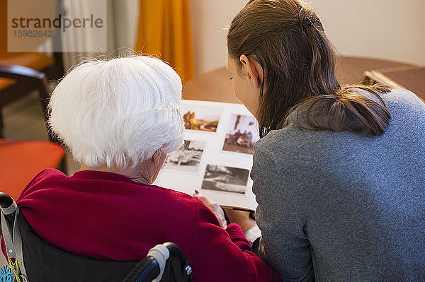 Großmutter mit Enkelin beim Betrachten eines Fotoalbums zu Hause