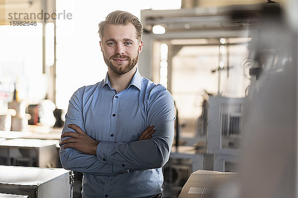 Porträt eines selbstbewussten jungen Geschäftsmannes in einer Fabrik