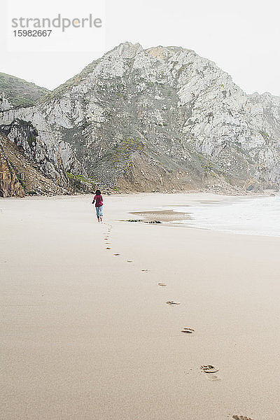 Frau hinterlässt Fußspuren beim Laufen am Strand von Ursa  Region Lisboa  Portugal