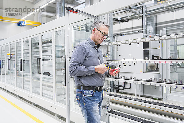 Mann mit Barcode-Scanner auf einem Produkt in einer Fabrik