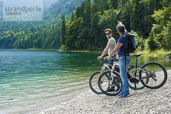 Senior und reifer Mann mit E-Bikes am Eibsee