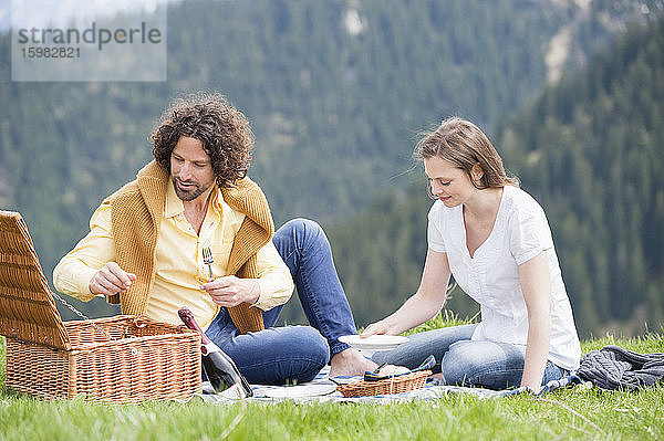 Mid adult couple enjoying picnic against mountain