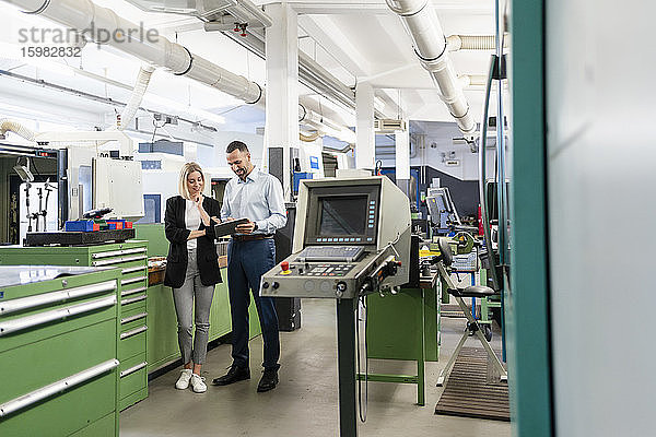 Geschäftsmann und Frau benutzen Tablet in einer Fabrikhalle