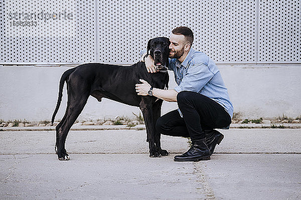 Glücklicher junger Mann  der seinen Hund im Freien knuddelt