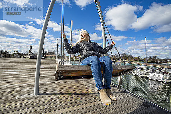 USA  Washington D.C.  Ältere Frau auf der Schaukel im Wharf District entlang des Potomac River