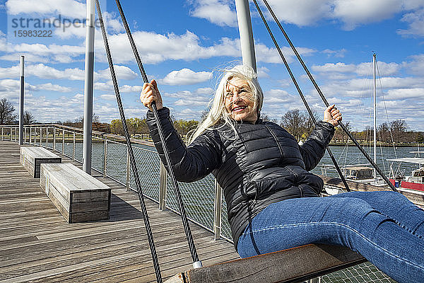 USA  Washington D.C.  Ältere Frau auf der Schaukel im Wharf District entlang des Potomac River