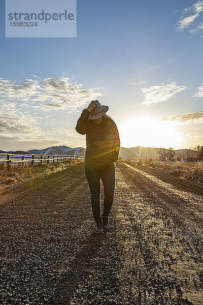 USA  Idaho  Sun Valley  Frau bei Sonnenaufgang auf der Landstraße
