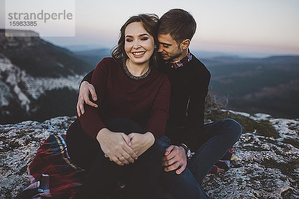 Ukraine  Krim  Junges Paar sitzt und umarmt sich am Canyon