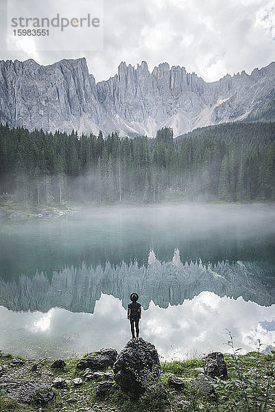Italien  Carezza  Junger Mann steht und schaut auf den Lago di Carezza in den Dolomiten