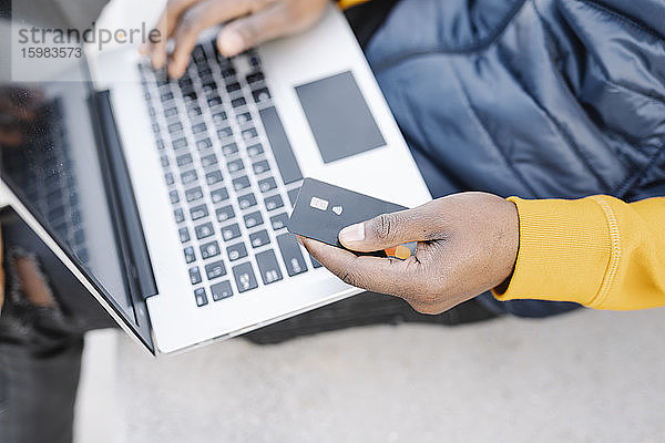 Nahaufnahme eines Mannes  der einen Laptop und eine Kreditkarte zum Online-Shopping benutzt