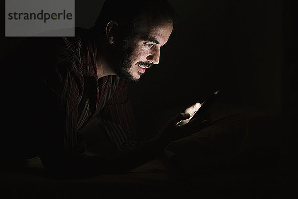 Mann benutzt Smartphone bei Nacht