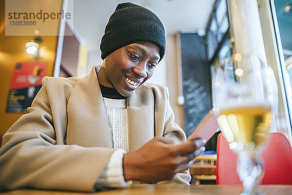 Glückliche junge Frau benutzt ihr Smartphone in einem Café