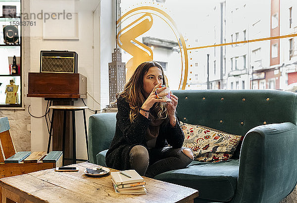 Frau trinkt Kaffee auf der Couch in einem Café