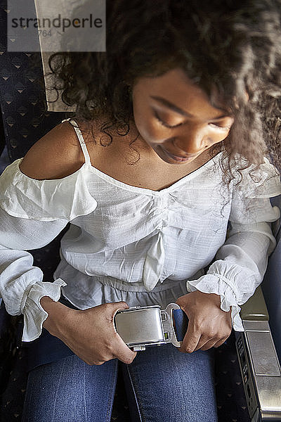 Hohe Winkel Ansicht der jungen weiblichen Passagier Befestigung Sicherheitsgurt beim Sitzen im Flugzeug