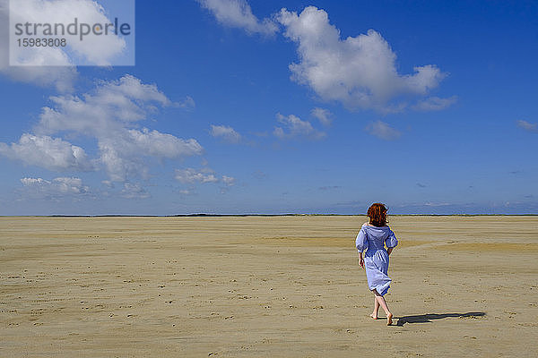 Volle Länge Rückansicht von Teenager-Mädchen zu Fuß auf Sand am Strand während des sonnigen Tages