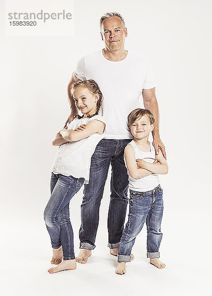 Porträt eines Vaters mit zwei Kindern vor einem weißen Hintergrund