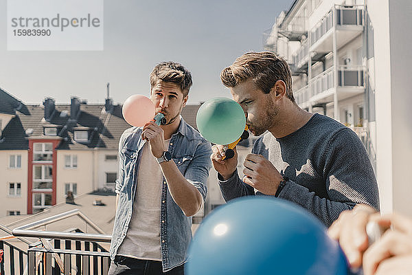 Gruppe von Freunden spielt mit Luftballons auf einem Balkon