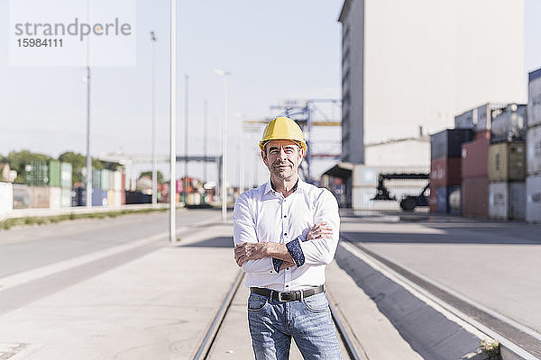 Porträt eines Geschäftsmannes mit Schutzhelm vor einem Industriegelände