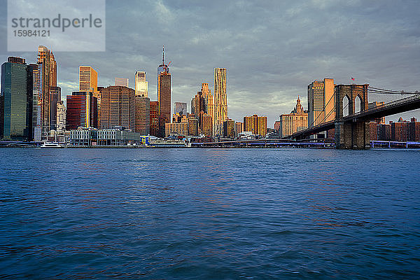 USA  New York  New York City  East River und Brooklyn Bridge in der Morgendämmerung mit der Skyline von Manhattan im Hintergrund