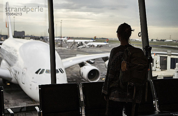 Südafrika  Johannesburg  Rückansicht einer Frau  die vom Flughafenterminal aus die Flugzeuge auf dem Rollfeld betrachtet