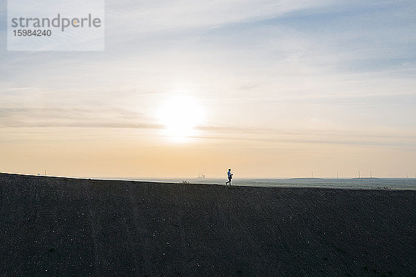 Männlicher Profi  der bei Sonnenuntergang auf einem Hügel spazieren geht